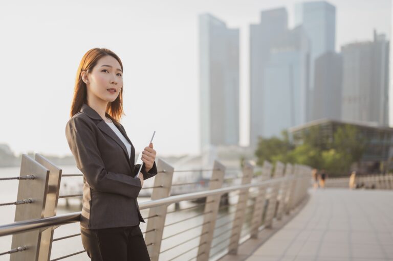 Asian business woman with Digital Tablet standing outdoors in financial city center