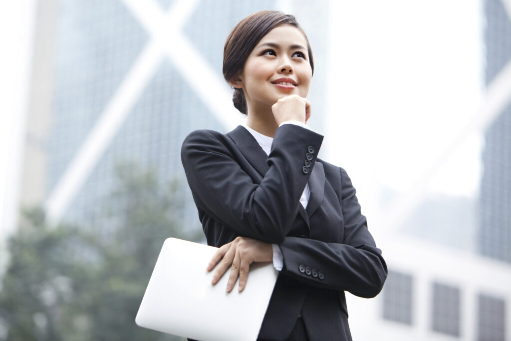Cheerful Chinese businesswoman hand on chin with digital tablet in hand, Hong Kong