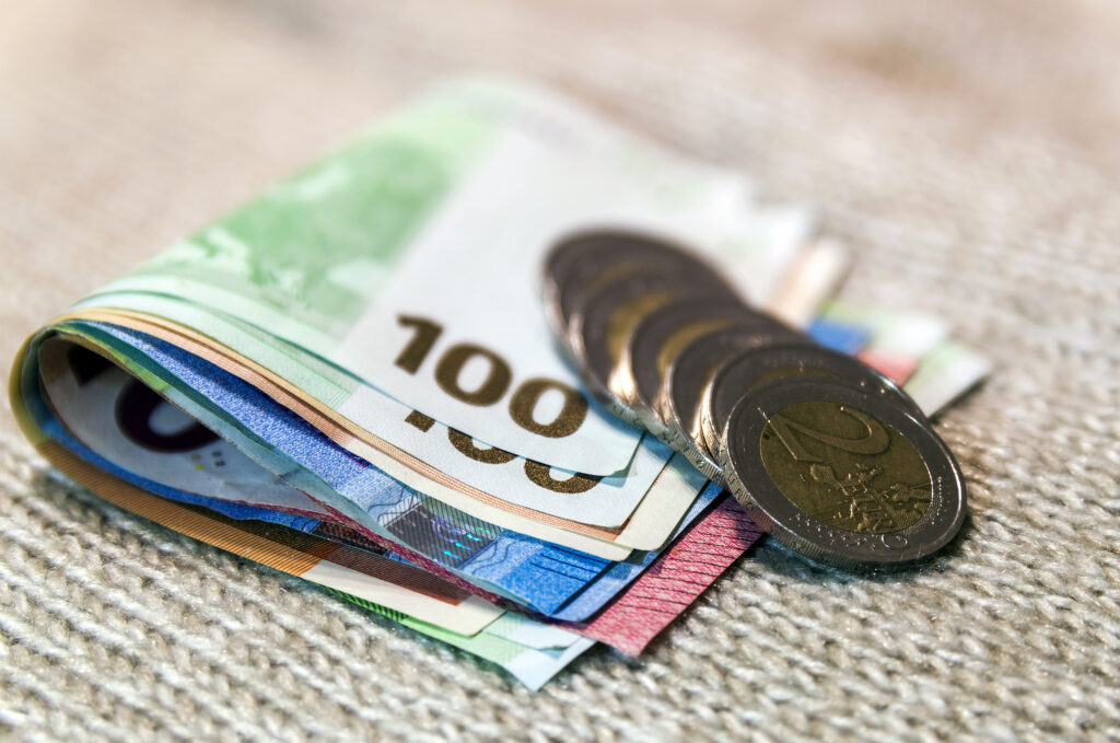Money euro coins and banknotes stacked on each other in different positions. Money concept. Detail of Euro currency on wool texture cloth background.