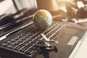 Toy airplane on laptop keyboard with globe and camera